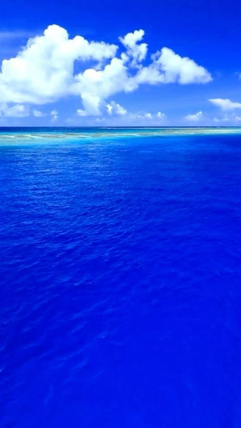 This may contain: the ocean is blue and clear with some clouds